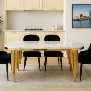 Autumn dining table with white marble top and sculptural gold cylindrical legs, styled in a bright modern interior.